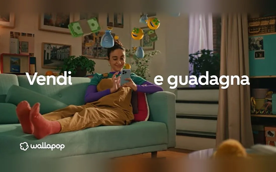 Wallapop Italy campaign still: a young woman on a sofa selling on her phone, with the line Vendi e guadagna